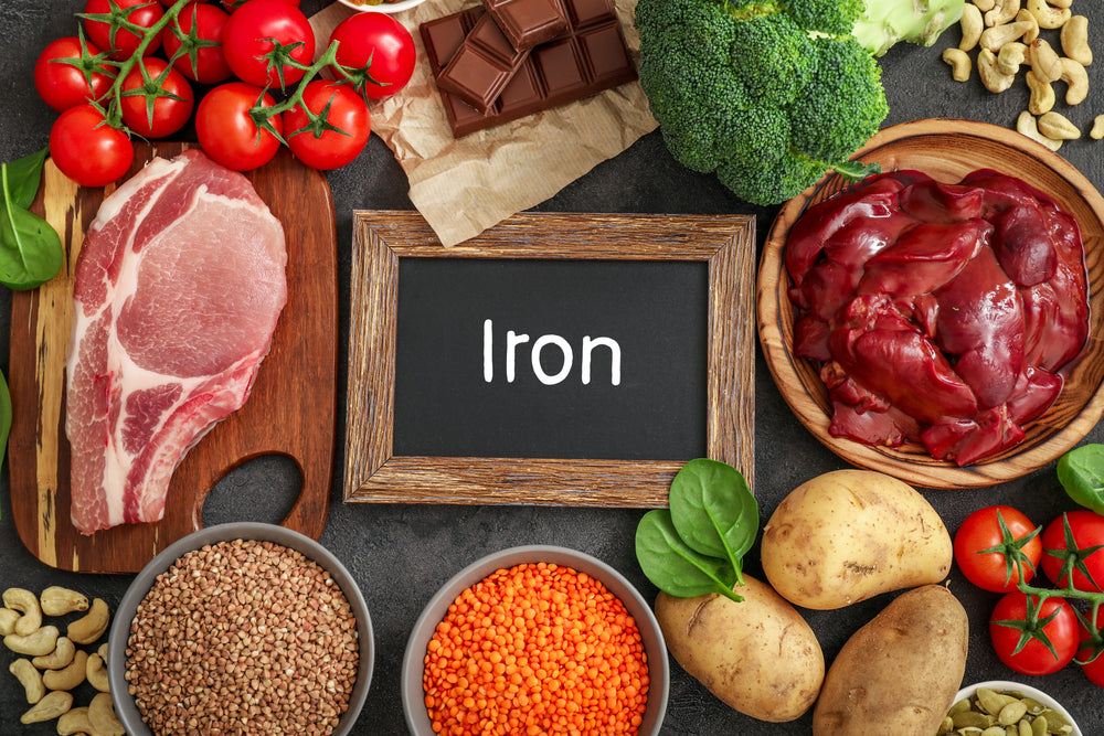 Assortment of high in Iron sources on dark background: liver, beef, keshew, buckwheat, spinach, tomatoes, potatoes, dark chocolate, lentil, broccoli. Top view.