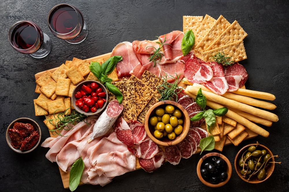 Appetizers with differents antipasti, charcuterie, snacks and red wine. Sausage, ham, tapas, olives and crackers for buffet party. Top view, flat lay.