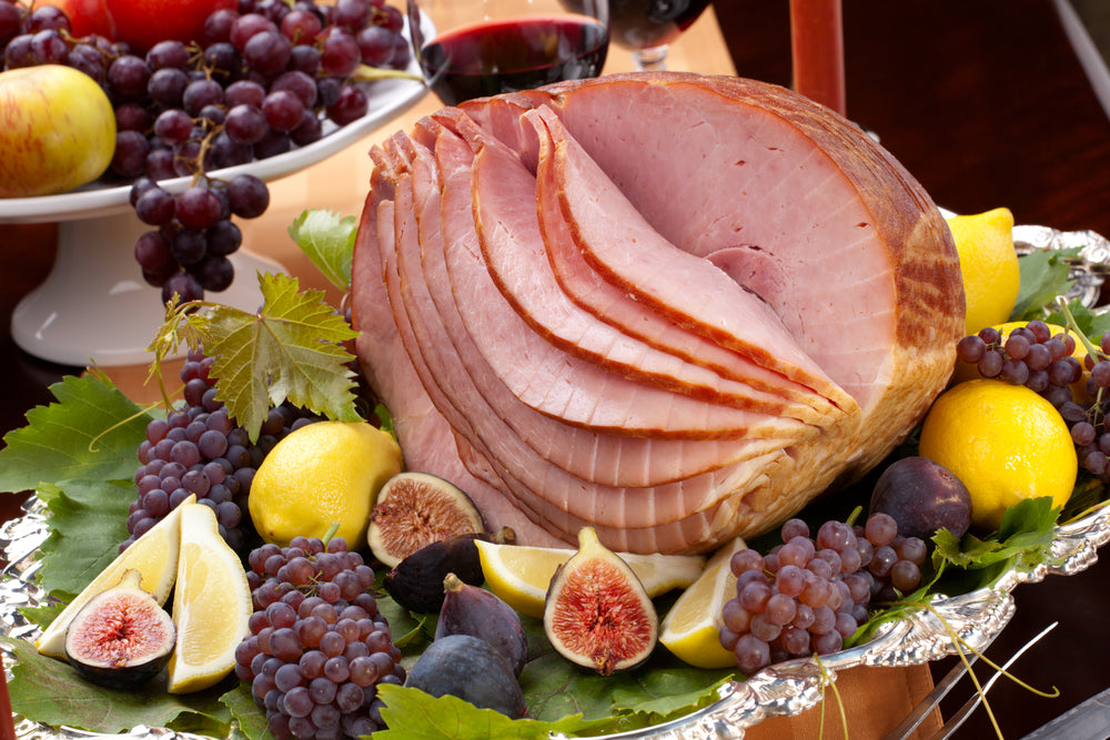 Glazed delicious whole baked honey sliced ham with figs, lemons and champagne grapes.